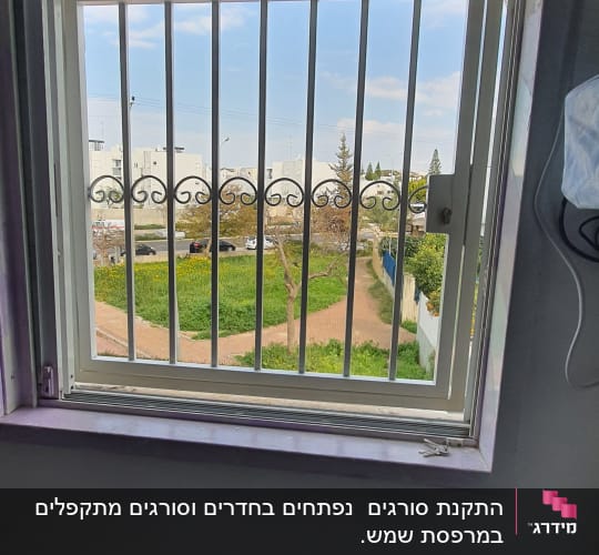 חלון עם סורגים מתכתיים ועיטורים מעוגלים